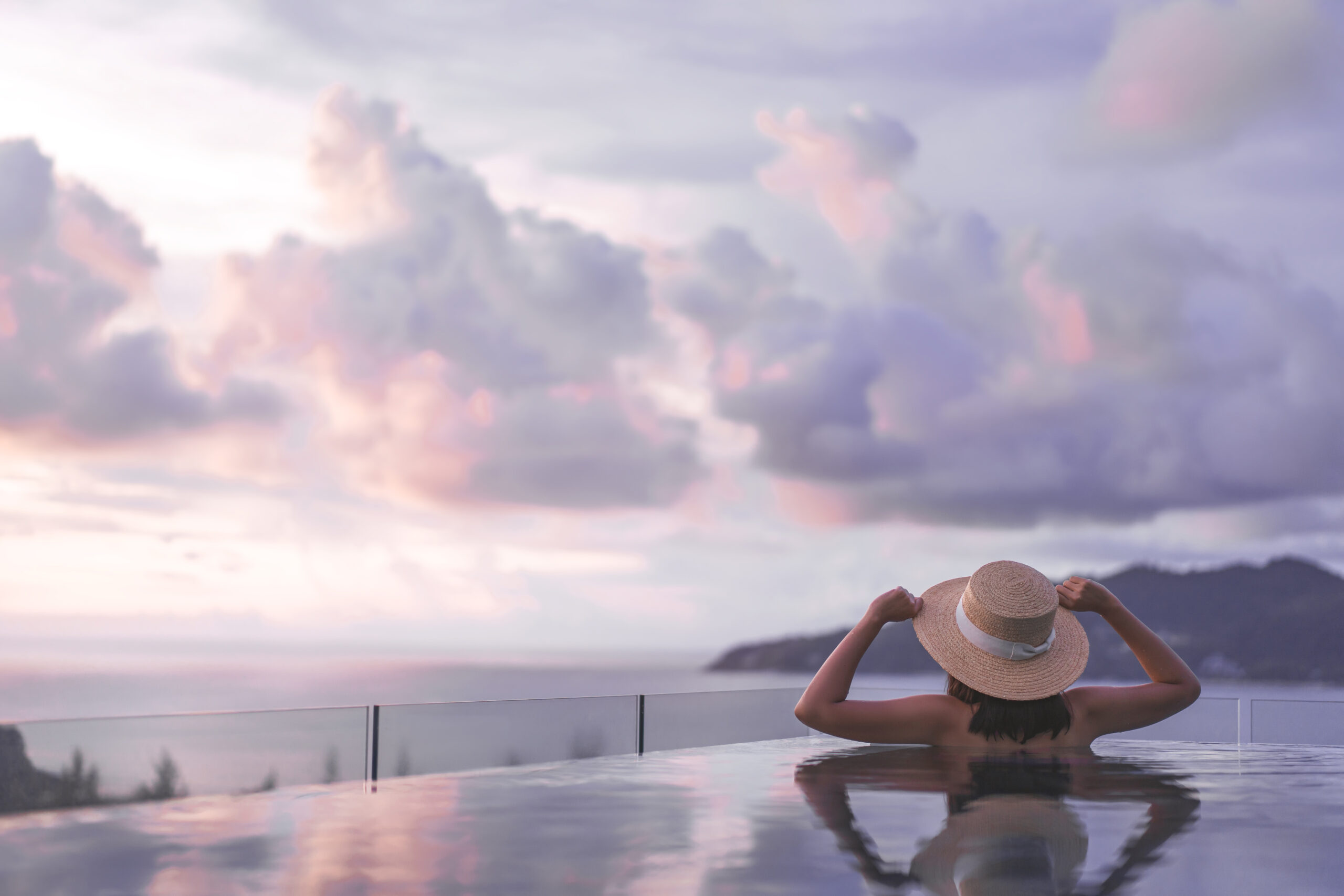 rear view woman relax at outdoor pool resort sea panorama view sunset sky on summer travel holiday.