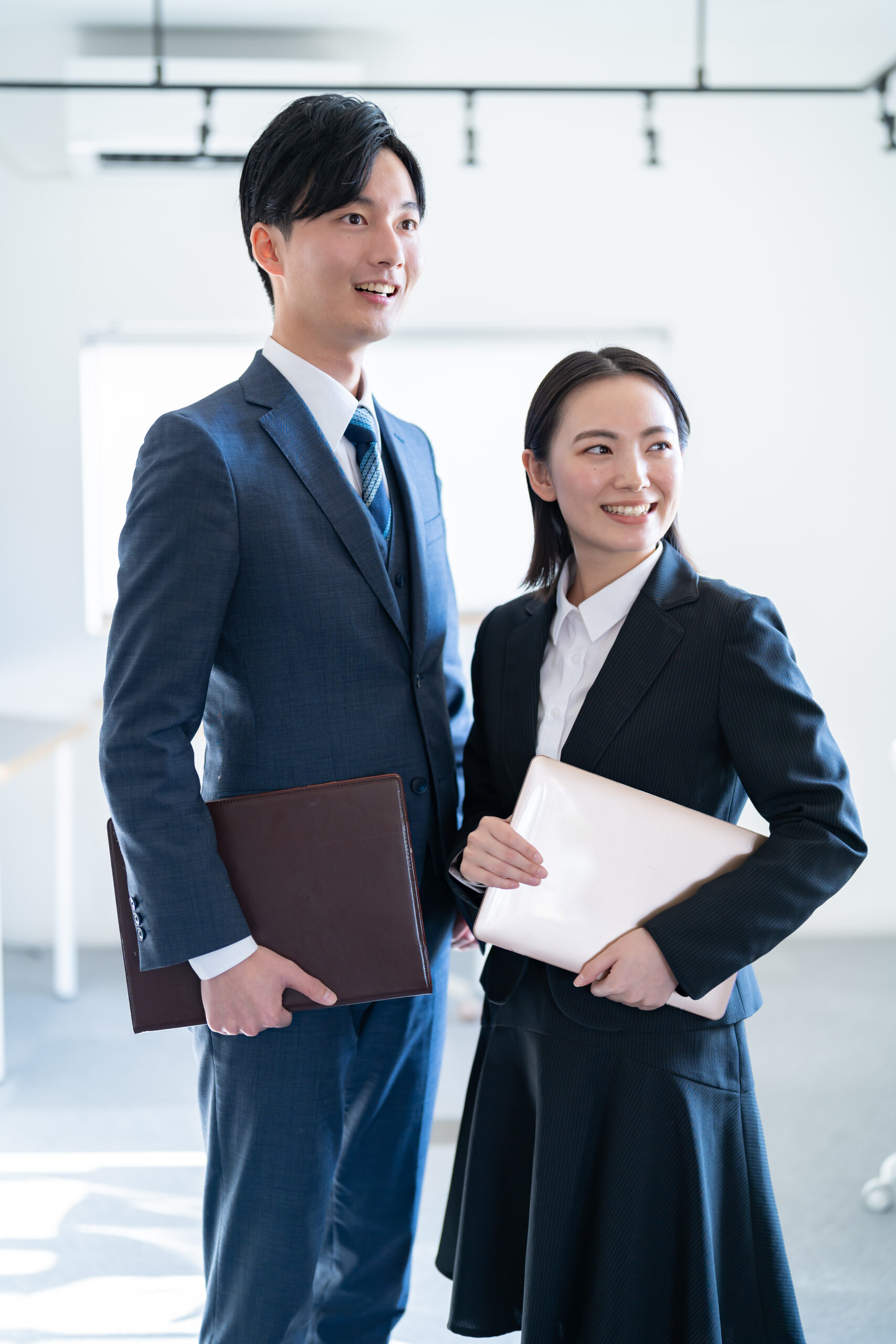 外を眺める笑顔の若手ビジネスマン2人